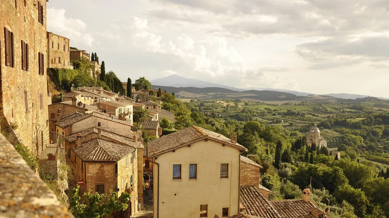 A hilltop Tuscan town of stone houses and tiled roofs looking out over vineyards and rolling green hills