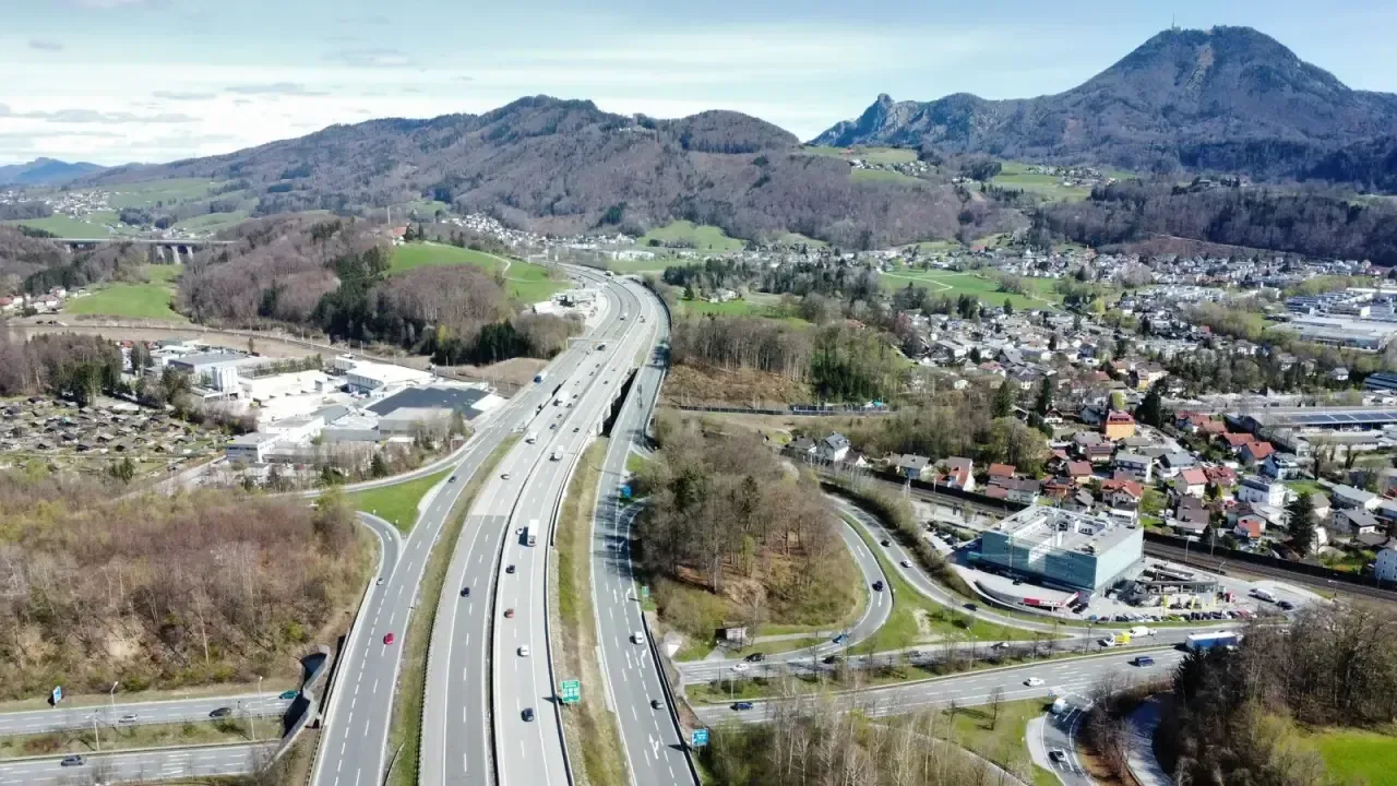 An aerial view of the Austrian A1 motorway curving through green hills near Salzburg
